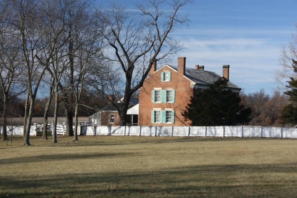 The Watkins family's brick farmhouse with green shutters behind a white plank fence