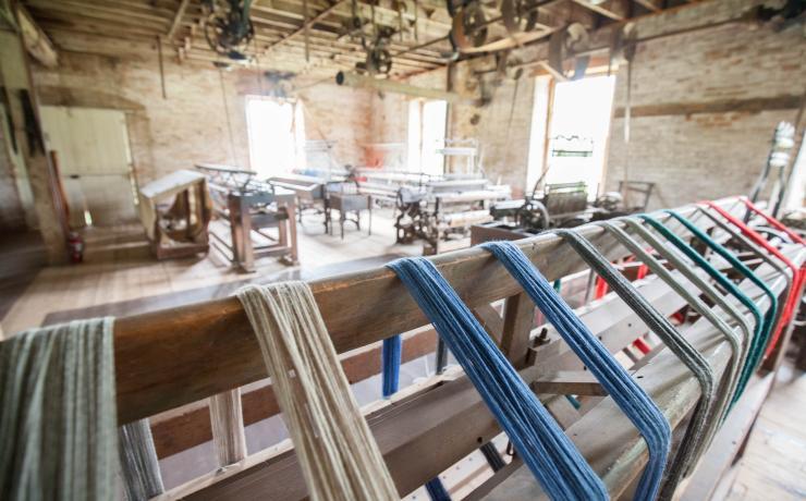 Skeins of blue, green and red wool yarn drying on a rack in the mill's loom room