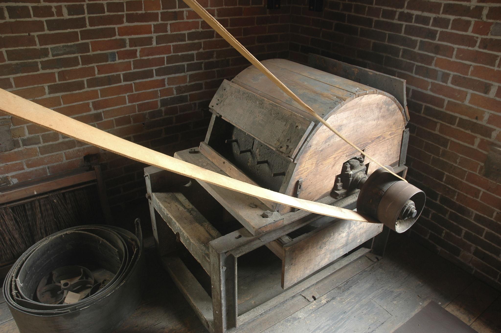 Original wooden wool-processing machine with leather drive belts inside the brick mill
