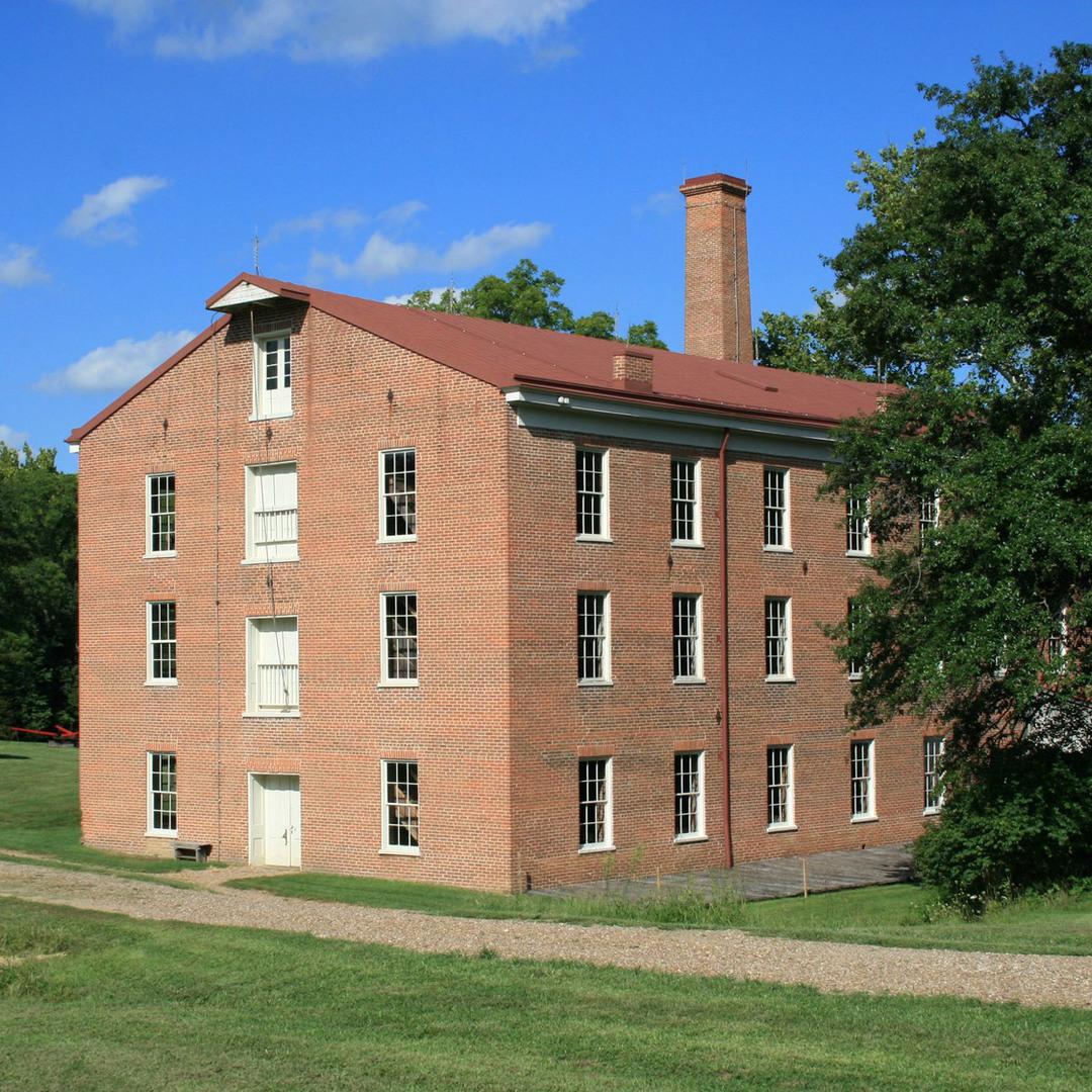 The three-story brick woolen mill with its tall chimney, completed in 1860