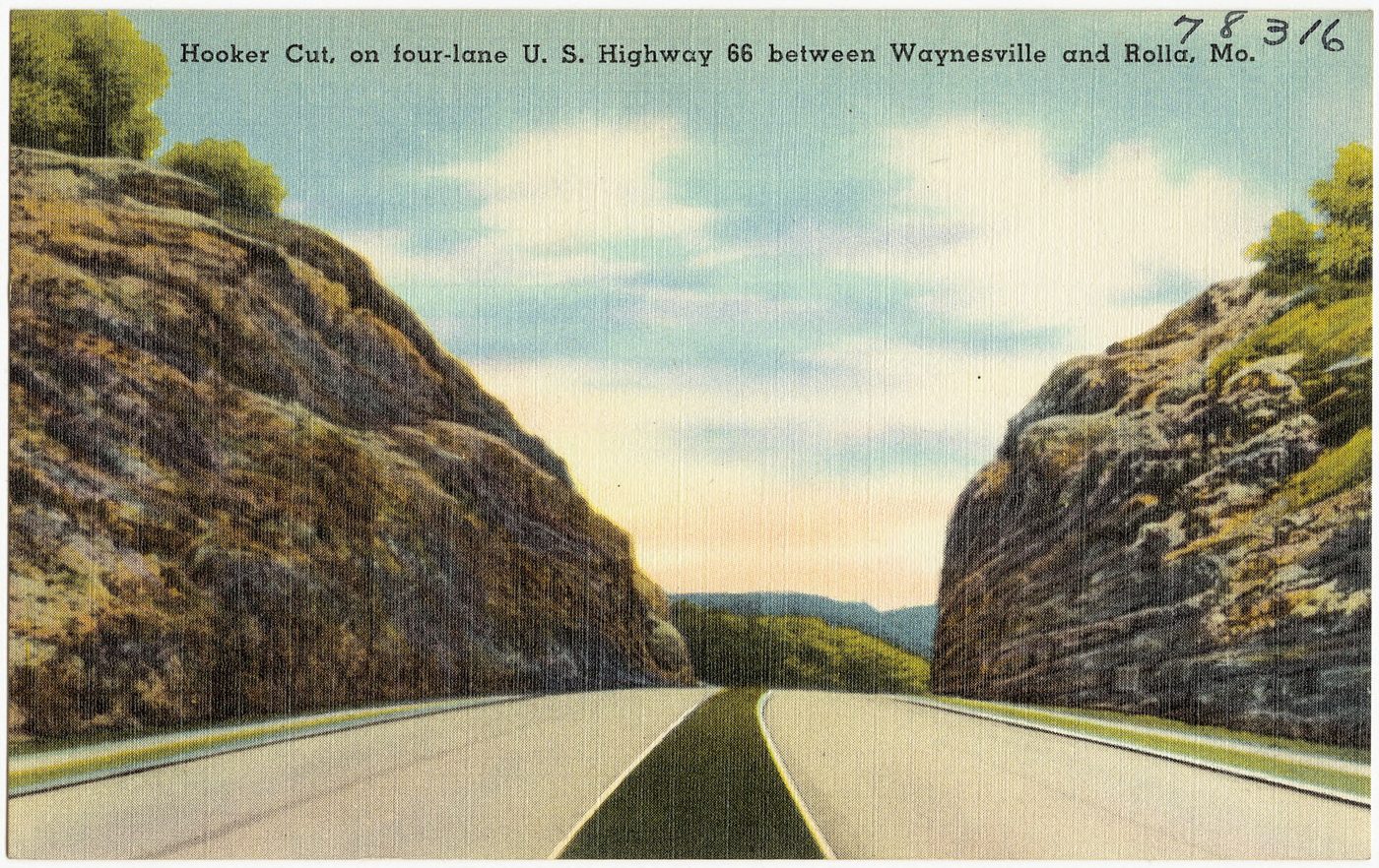 Vintage color postcard of a divided four-lane highway running through a deep rock cut with sheer limestone walls on both sides