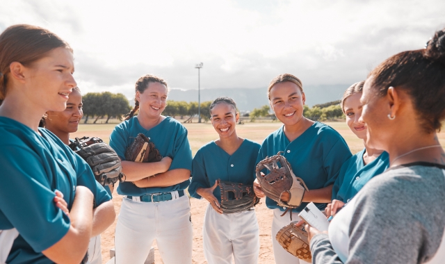 Group of young softball players standing in a huddle on the field.