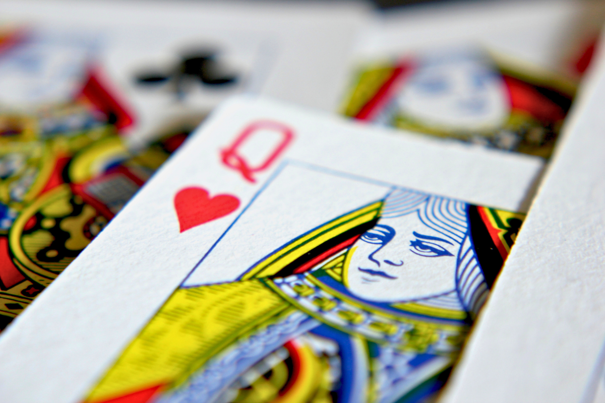 A queen of hearts playing card laying on top of other cards.