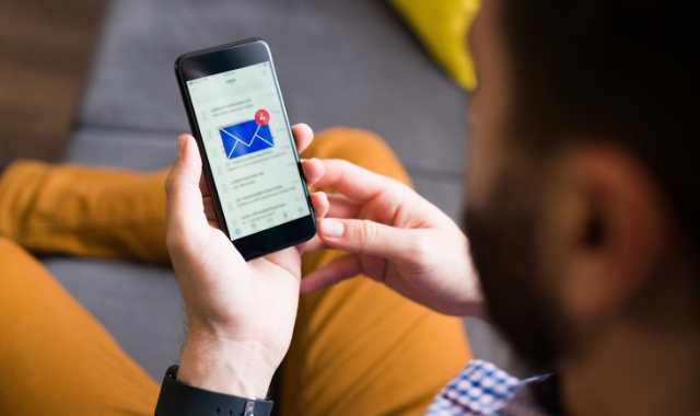 Man holding his phone and looking at his email inbox.