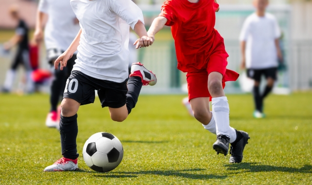 Feet running on a field and kicking a soccer ball.